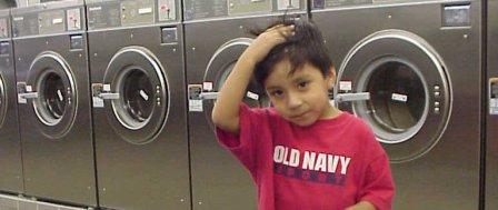A kid standing in front of washing machines at a laundromat